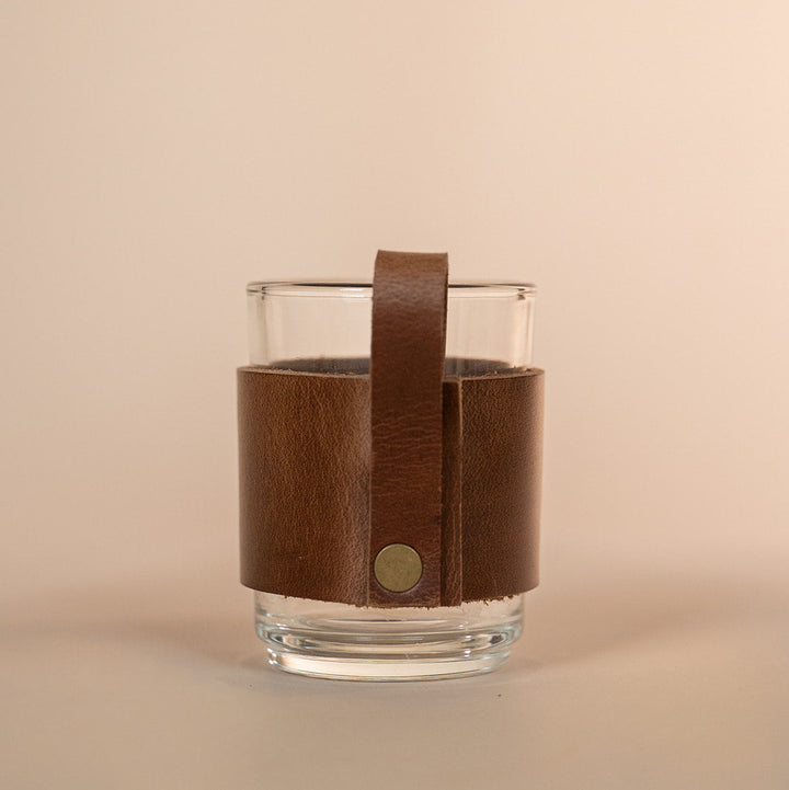 Clear glass with a brown leather sleeve featuring a Texas A&amp;M stamped debossed logo on a beige background