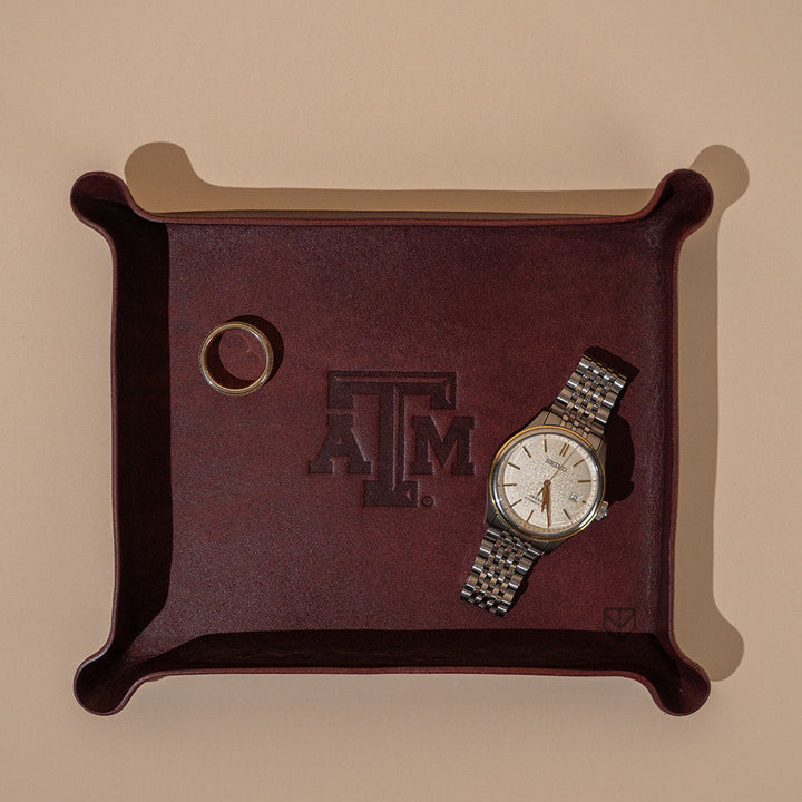 Maroon leather valet tray with Texas A&amp;M Aggies logo and gold watch and gold Aggie ring
